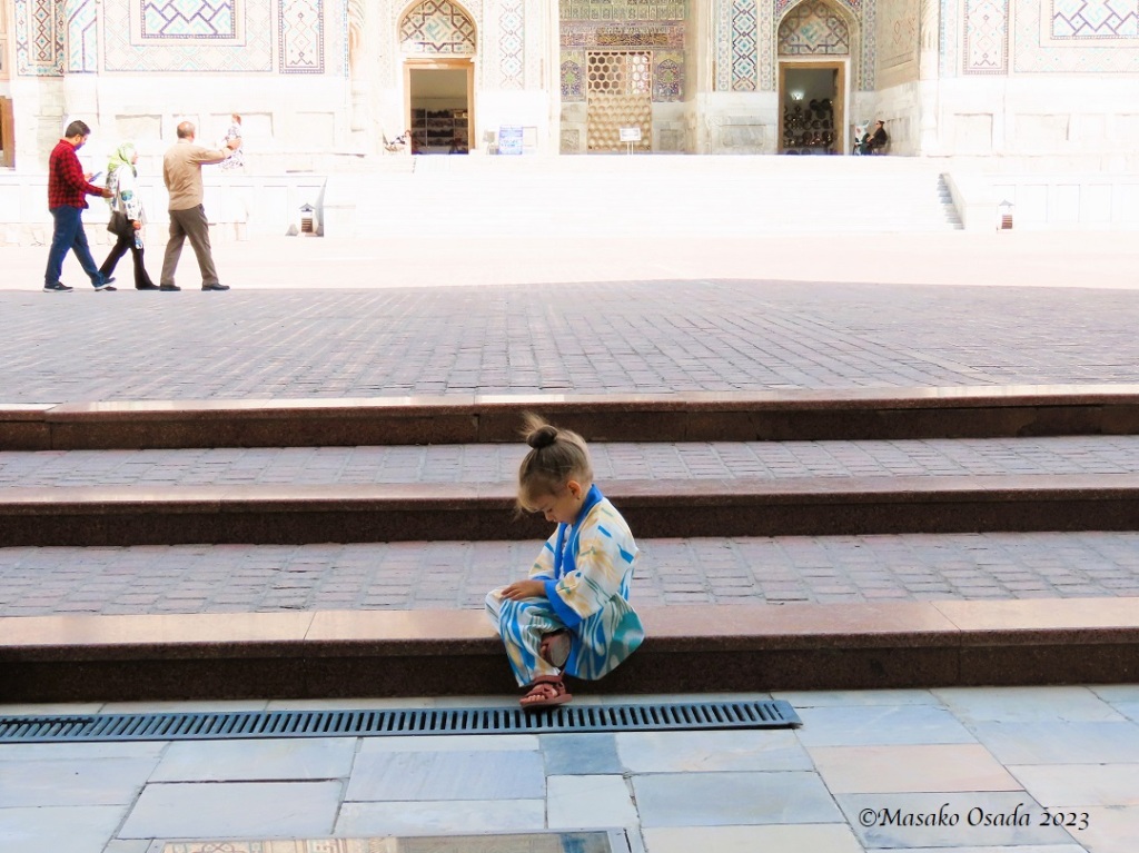 Small girl looking at cell phone. Samarkand, Uzbekistan